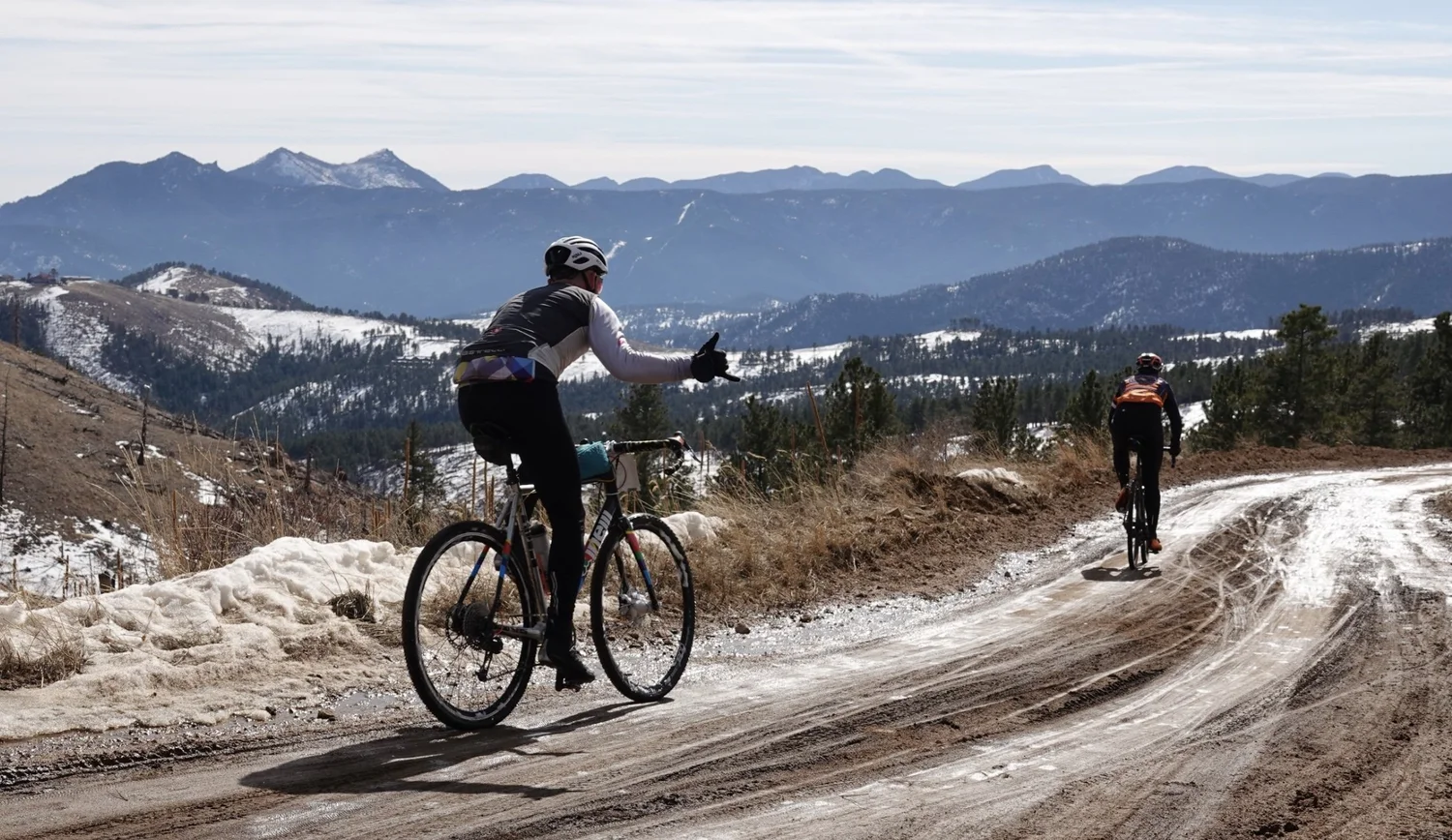 A cyclist climbing a winter canyon road with mountain views